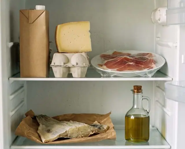 O interior de um frigorífico: leite, queijo, ovos, fiambre, peixe e azeite